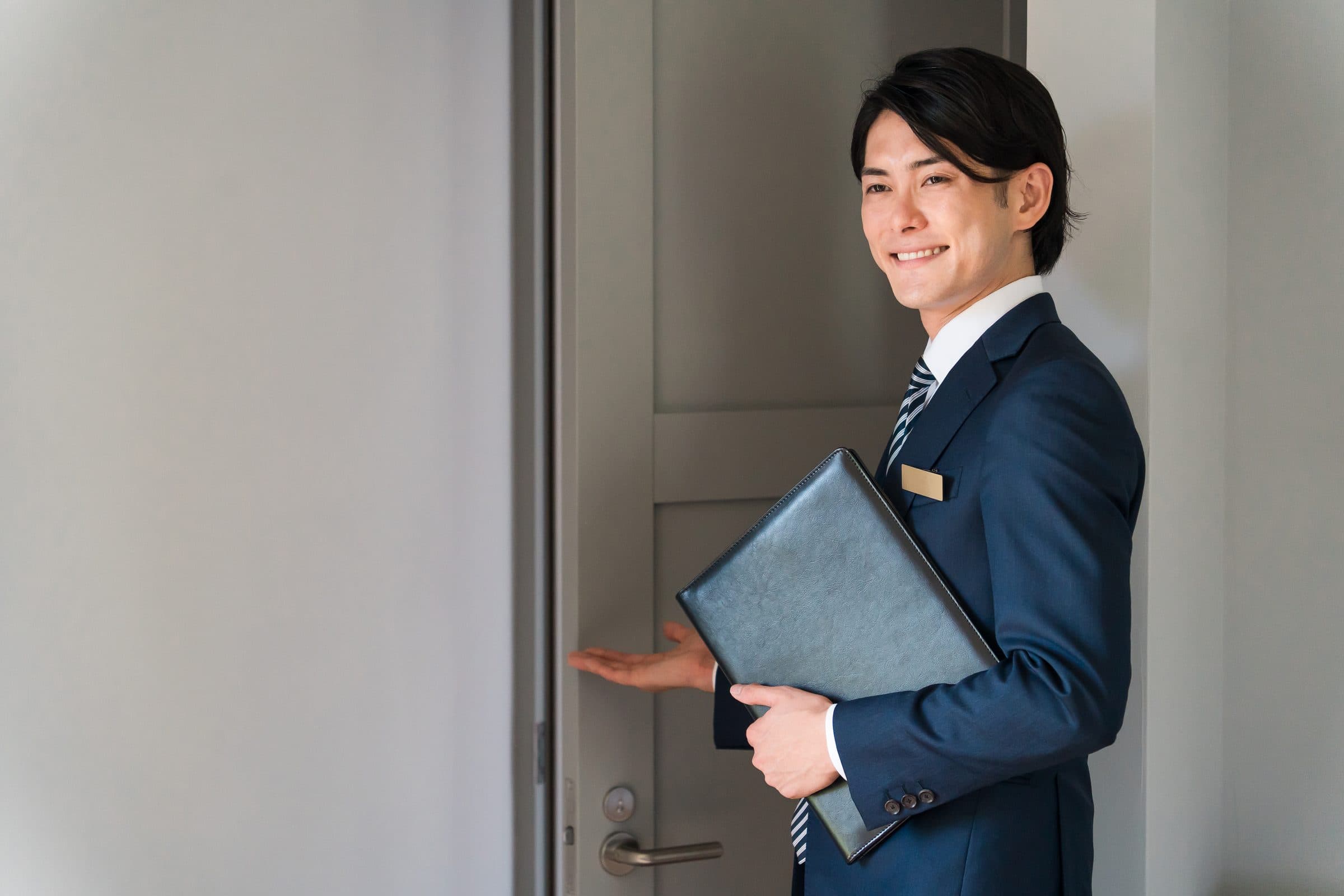 扉を開けて案内する人物のイメージ